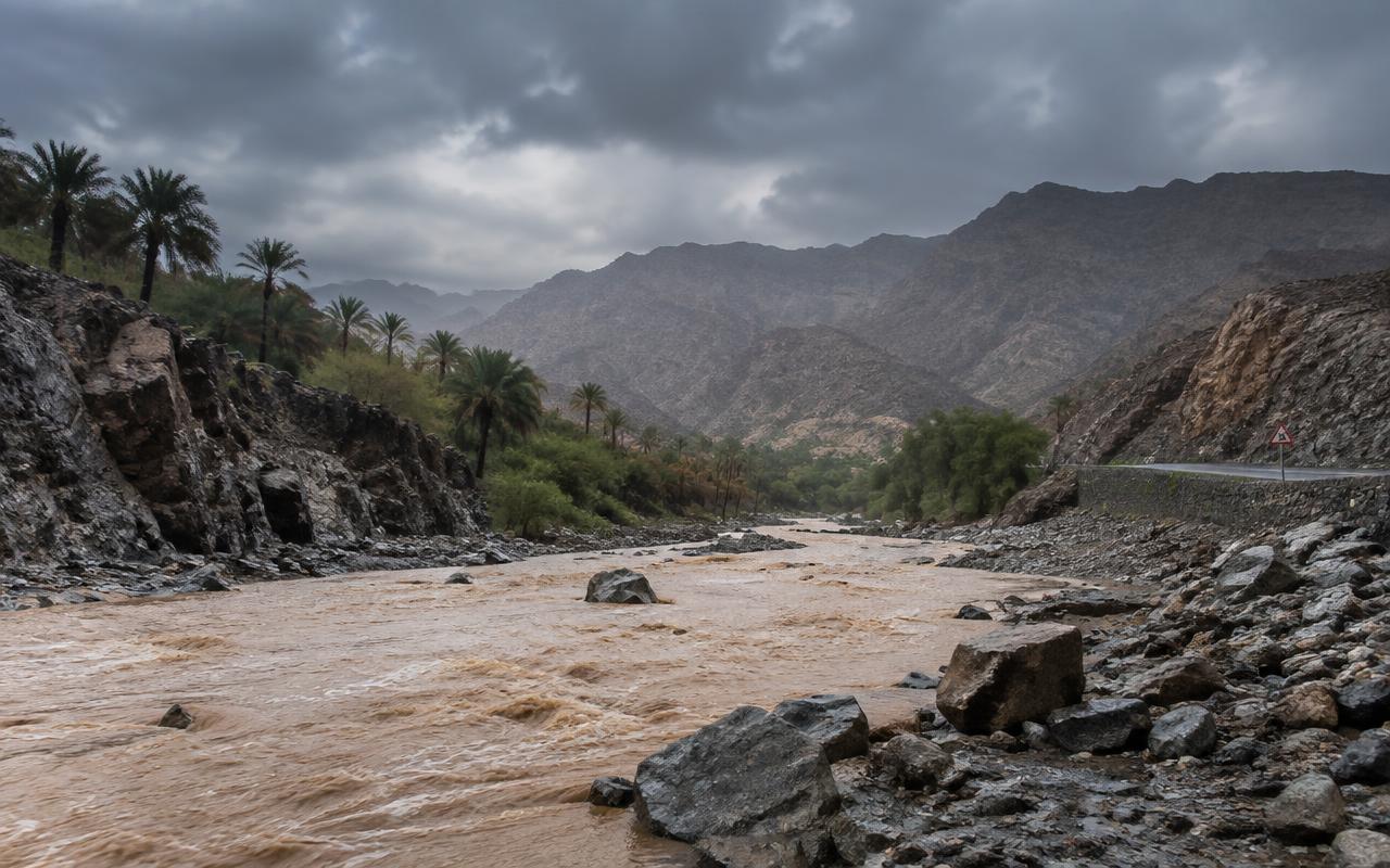 A calm wadi after rain, water reflecting the mountains